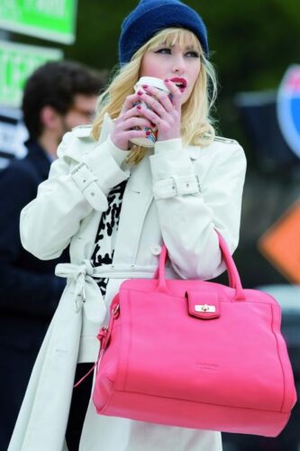 Mannequin vêtue d’un trench-coat blanc élégant, portant un sac à main rose vif, accessoire contrastant et tendance, avec une tasse à la main, style urbain sophistiqué.