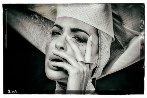 Mannequin en noir et blanc, maquillage expressif, chapeau de style avant-gardiste, pose dramatique soulignant l'émotion et l'esthétique haute couture.