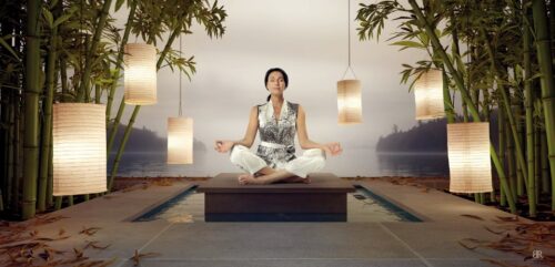Mannequin en tailleur argenté et pantalon blanc, assise en position de méditation dans un décor zen, illustrant une élégance contemporaine et un style décontracté-soigné.