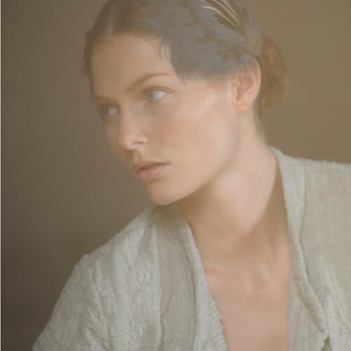 Mannequin portant un cardigan texturé ivoire, coiffure simple et maquillage naturel, dans une ambiance douce et vaporeuse qui rappelle l’élégance minimaliste contemporaine.