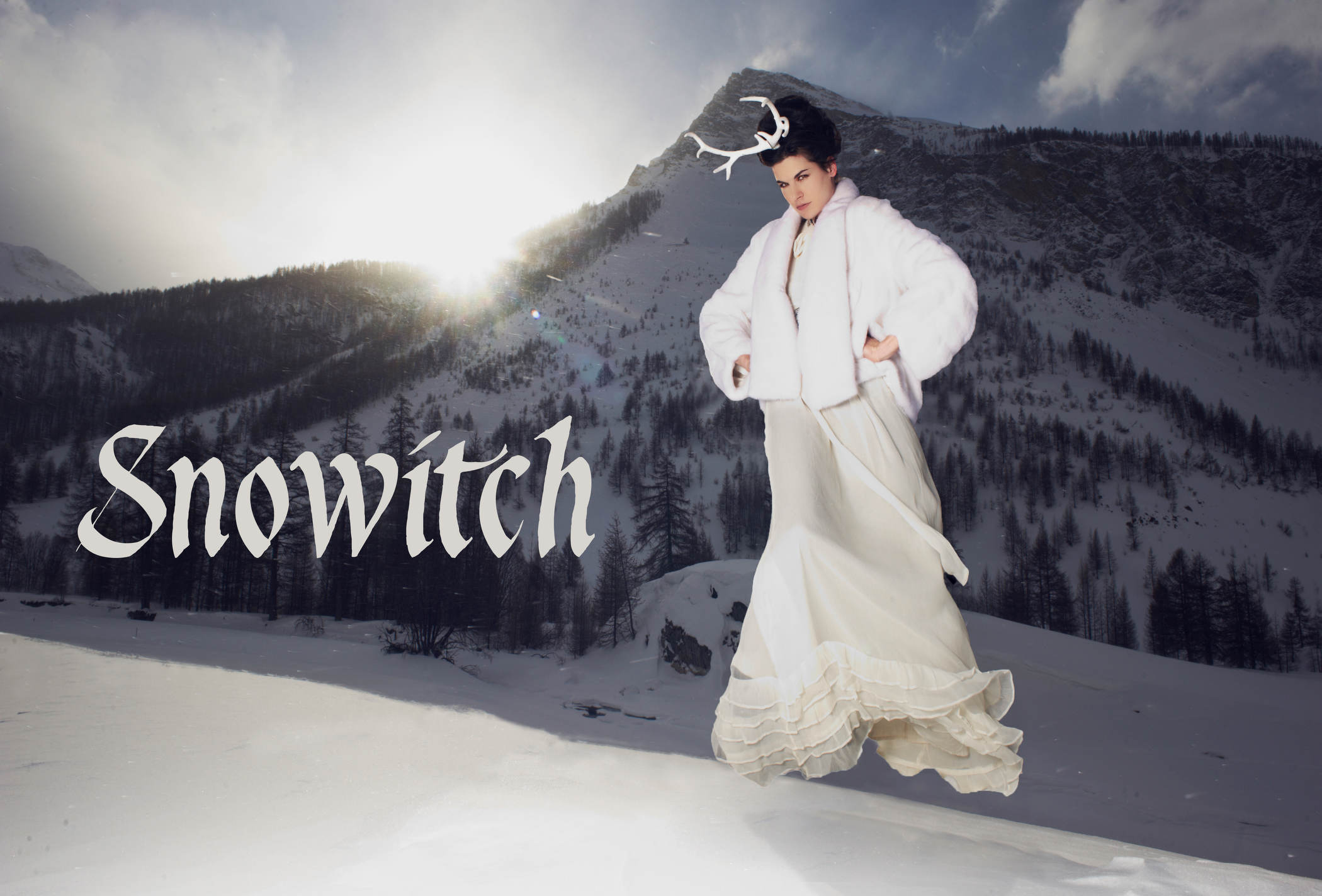 mannequin pose dans la neige avec une jupe longue blanche et un manteau ample, accessoirisé de cornes, pour un look d’inspiration hivernale élégante et théâtrale.