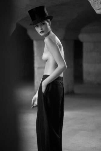 Mannequin posant dans un espace architectural, portant un pantalon noir ample, style minimaliste en noir et blanc, évoquant l’élégance contemporaine et la confiance en soi.