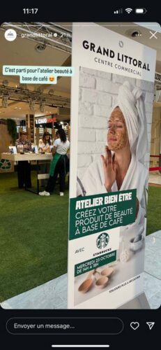 Installation scénographique organisée autour d’un atelier bien-être, comprenant une décoration végétalisée, un comptoir et un panneau promotionnel valorisant les produits de beauté à base de café.