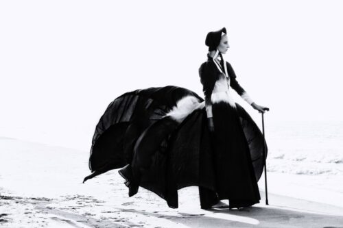Mannequin en robe noire volumineuse et élégante, touche victorienne, accessoires raffinés, pose sophistiquée sur un fond minimaliste.