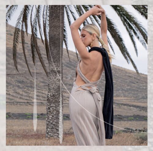 Femme élégante portant une robe Prêt-à-porter Maison Monzerian, posant devant un palmier dans un paysage naturel, mettant en valeur la mode de luxe moderne.