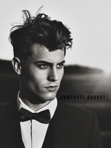 Mannequin masculin élégant en smoking noir avec nœud papillon, coiffure travaillée, pose sophistiquée en extérieur, ambiance mode contemporaine, photographie en noir et blanc.
