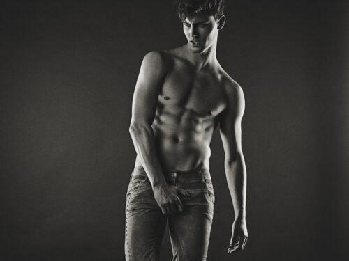 Mannequin masculin torse nu pose en jean, style artistique en noir et blanc, mettant en valeur la musculature et l’attitude mode contemporaine.