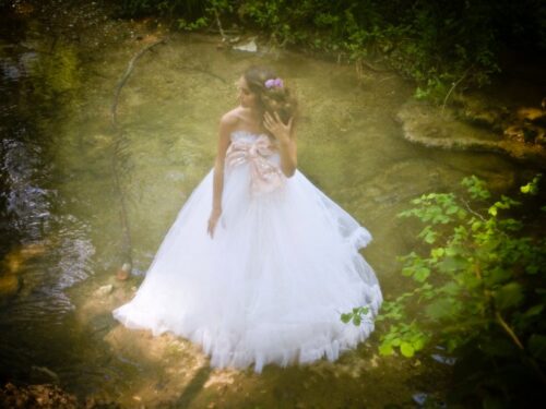 Mannequin portant une élégante robe de mariée blanche à jupe volumineuse, posé dans un décor naturel et romantique, l’ensemble offrant une allure féerique et sophistiquée.